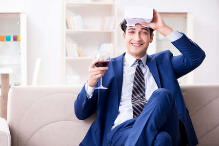 Businessman drinking wine sitting at homeの写真素材