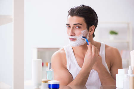 Young handsome man shaving early in the morning at homeの写真素材
