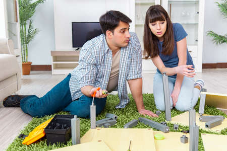 Young family assembling furniture at new house