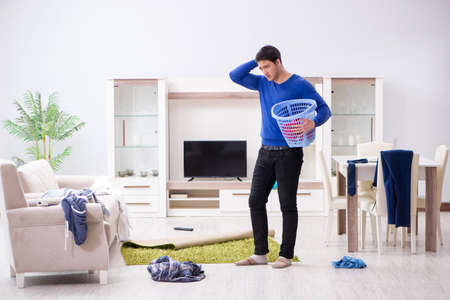 Young man collecting dirty clothing for laundryの写真素材