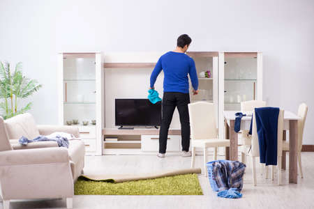 Young man collecting dirty clothing for laundryの写真素材