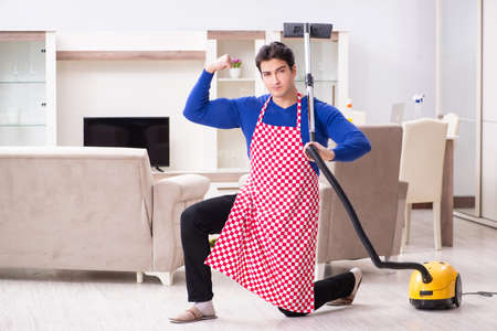 Young man vacuum cleaning his apartmentの写真素材