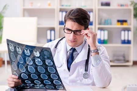 Young doctor looking at x-ray images in clinic