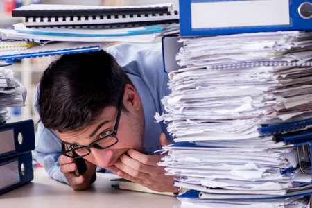 Extremely busy businessman working in officeの写真素材