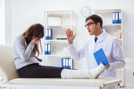 Doctor examining patient with broken legの写真素材