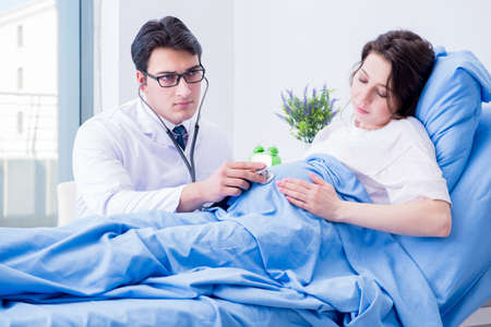 Doctor visiting pregnant in hospital roomの写真素材