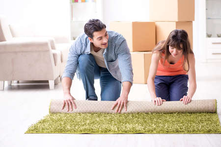 Young family rolling carpet at new apartmentの写真素材