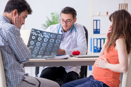 Pregnant woman with her husband visiting the doctor in clinicの写真素材