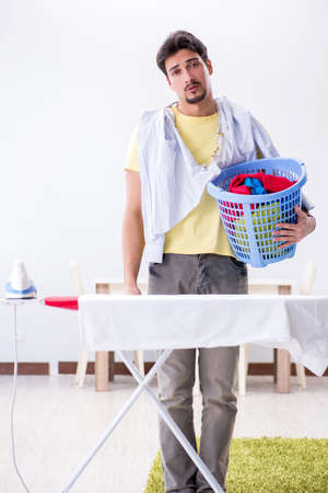 Handsome man husband doing clothing ironing at homeの写真素材