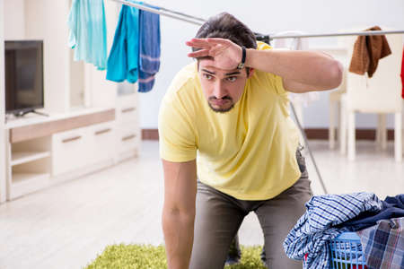 Handsome man husband doing laundering at homeの写真素材