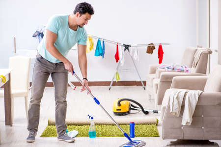Young attractive man husband doing mopping at homeの写真素材