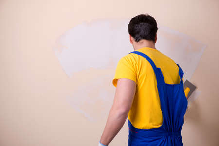 Young contractor employee applying plaster on wallの写真素材