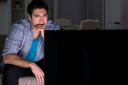 Young man watching tv late at night