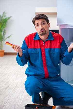 Professional contractor repairing broken fridgeの写真素材