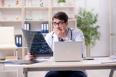 Young doctor looking at x-ray images in clinicの写真素材