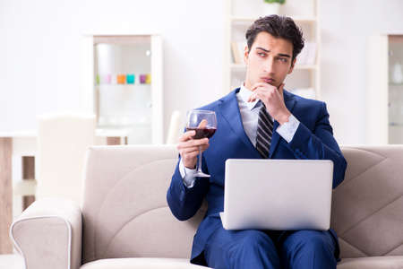 Businessman drinking wine sitting at homeの写真素材