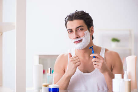 Young handsome man shaving early in the morning at homeの写真素材