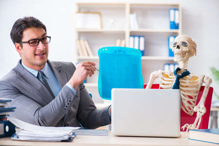 Businessman working with skeleton in officeの写真素材