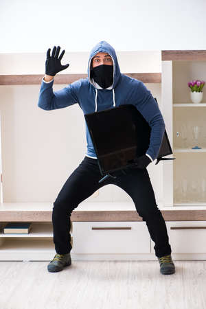 Man burglar stealing tv set from houseの写真素材