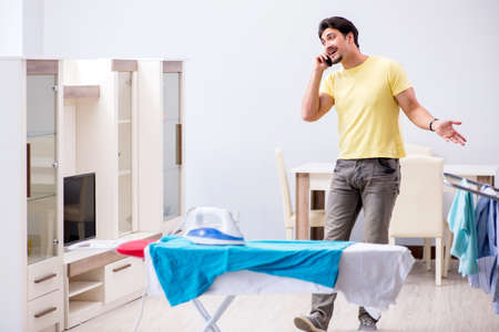 Handsome man husband doing clothing ironing at homeの写真素材