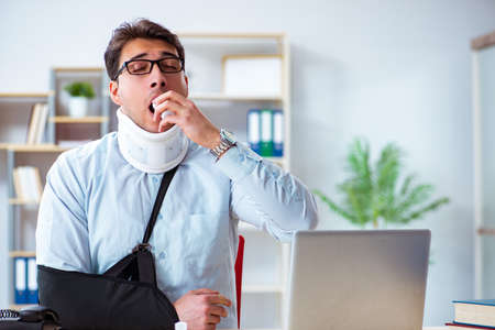 Businessman with broken arm working in officeの写真素材