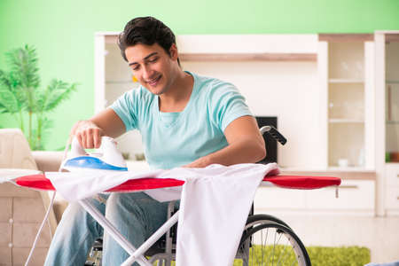 Disabled man on wheelchair ironing clothingの写真素材