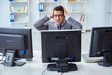 Businessman sitting in front of many screensの写真素材