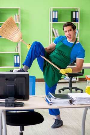 Young male handsome professional cleaner cleaning floor with bro