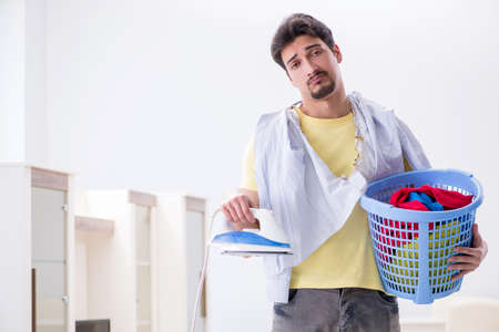 Handsome man husband doing clothing ironing at homeの写真素材