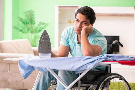 Disabled man on wheelchair ironing clothingの写真素材