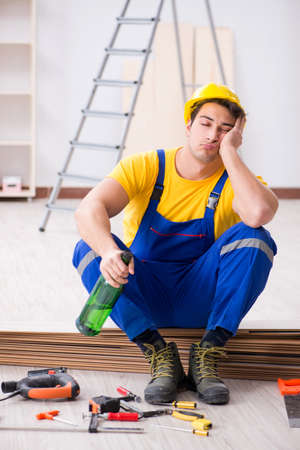 Floor repairman drinking alcohol during breakの写真素材