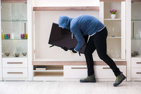Man burglar stealing tv set from houseの写真素材