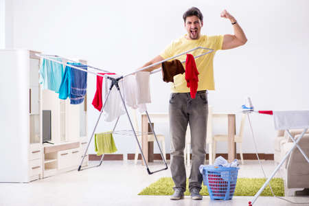 Handsome man husband doing laundering at homeの写真素材