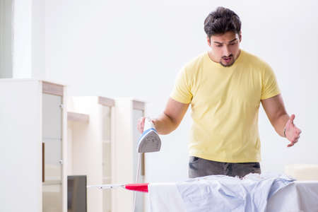 Handsome man husband doing clothing ironing at homeの写真素材