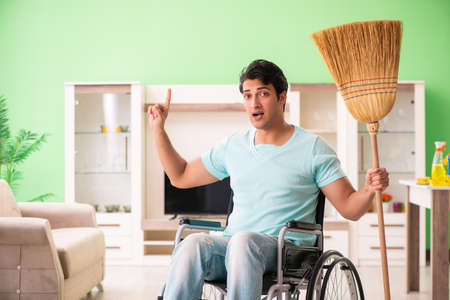 Disabled man on wheelchair cleaning houseの写真素材