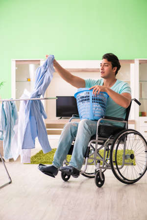 Disabled man on wheelchair doing laundryの写真素材