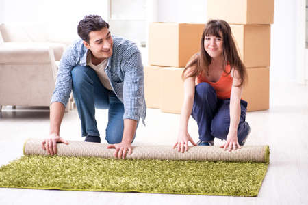 Young family rolling carpet at new apartmentの写真素材