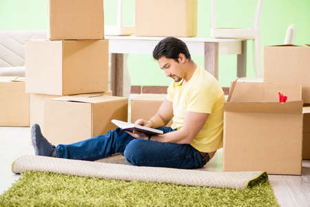 Young handsome man moving in to new house with boxesの写真素材