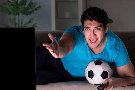 Young man watching football late at nightの写真素材