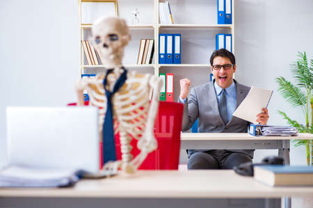 Businessman working with skeleton in officeの写真素材