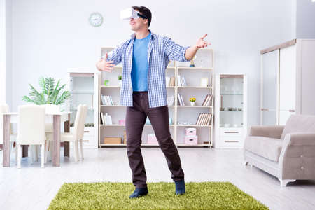 Man with virtual reality glasses playing at home