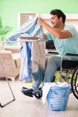 Disabled man on wheelchair doing laundryの写真素材