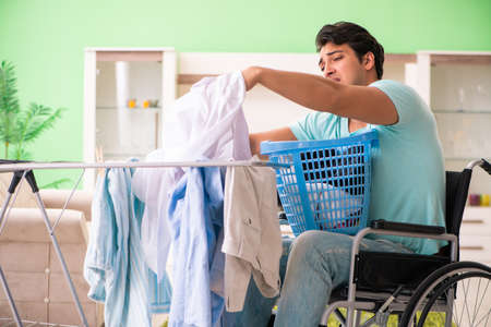 Disabled man on wheelchair doing laundryの写真素材