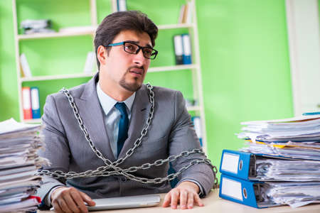 Employee chained to his desk due to workloadの写真素材
