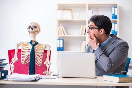 Businessman working with skeleton in officeの写真素材
