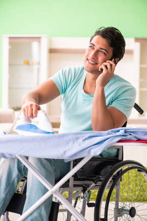 Disabled man on wheelchair ironing clothingの写真素材