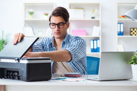 Young man employee working at copying machine in the office