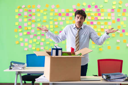 Man collecting his stuff after redundancy in the office with manの写真素材