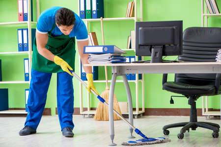 Male handsome professional cleaner doing mopping in the office