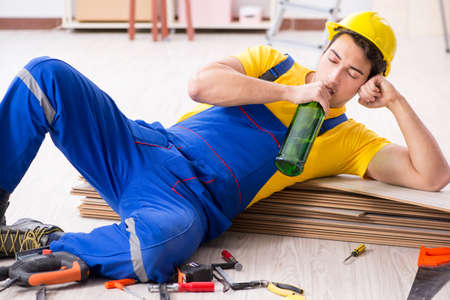 Floor repairman drinking alcohol during breakの写真素材